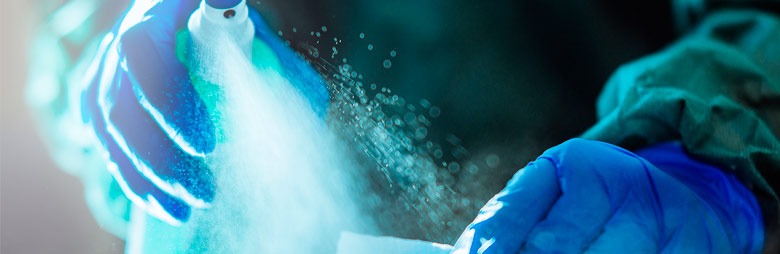 A gloved cleaner applying a disinfectant for use in the airplane cabin.