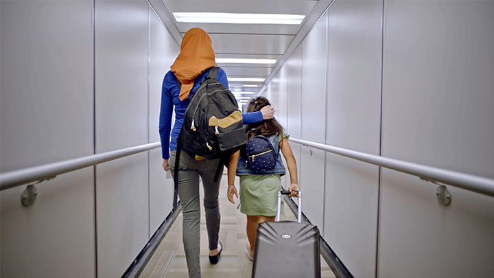 A family walking down a jet way together to board an airplane that has been cleaned and disinfected.