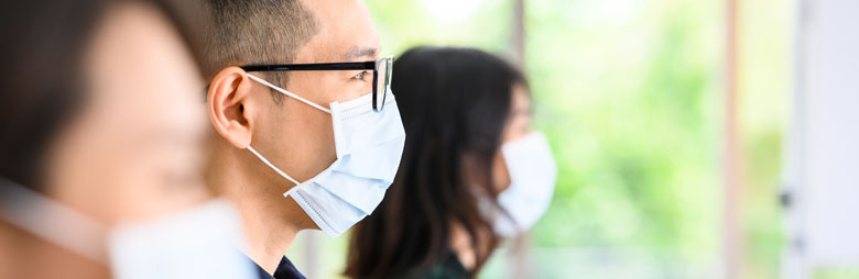 A diverse team of people wearing masks while meeting to discuss their work together.