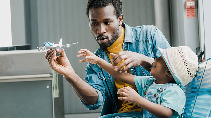A father using a toy airplane with his young son.